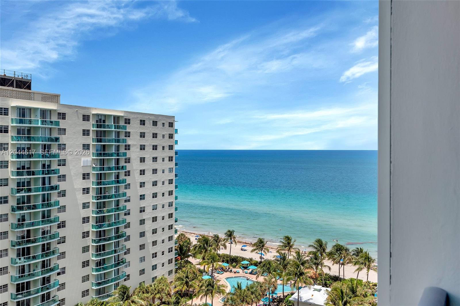 A high-rise building overlooks a sandy beach, palm trees, a swimming pool, and the ocean — 4001 S Ocean Dr # 14H, Hollywood FL 33019, HOLLYWOOD, FL