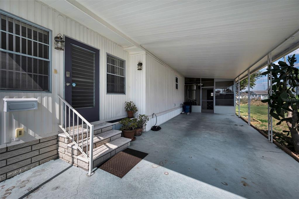 A covered carport leads to the front entrance of a mobile home with exterior stairs — 3230 LANARK DRIVE, HOLIDAY, FL