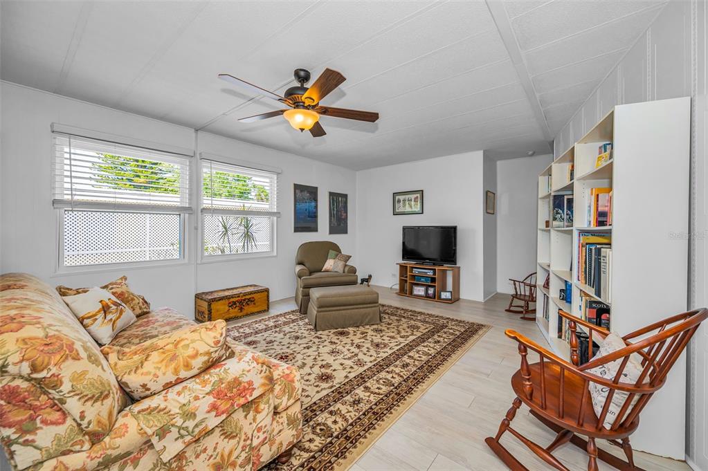 A living room features a floral sofa, a patterned area rug, and a wooden rocking chair — 3230 LANARK DRIVE, HOLIDAY, FL