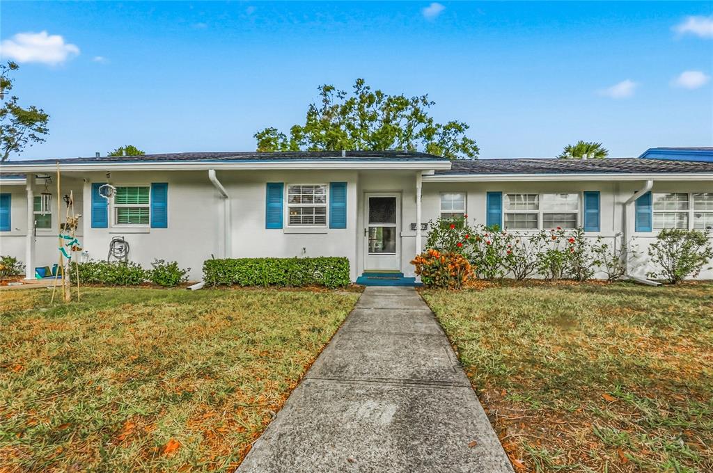 A single-story white house with blue shutters and a concrete walkway leading to the entrance — 249 N HILL AVENUE UNIT 30, DELAND, FL