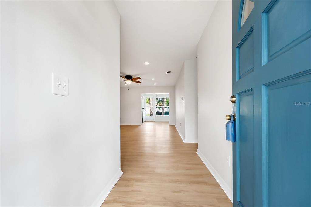 An entryway with light wood flooring leads to a living area with a ceiling fan — 249 N HILL AVENUE UNIT 30, DELAND, FL