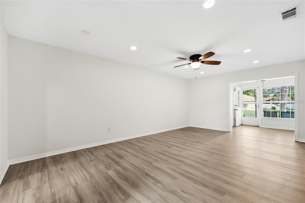 An empty room with light wood-look flooring, white walls, a ceiling fan, and a doorway — 249 N HILL AVENUE UNIT 30, DELAND, FL