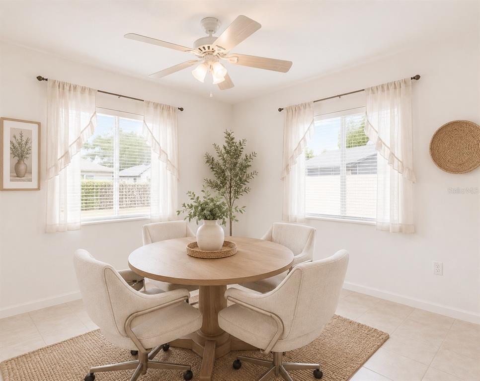 A bright dining room features a round wooden table, four upholstered chairs, and two windows — 7115 LEXINGTON CIRCLE, BROOKSVILLE, FL