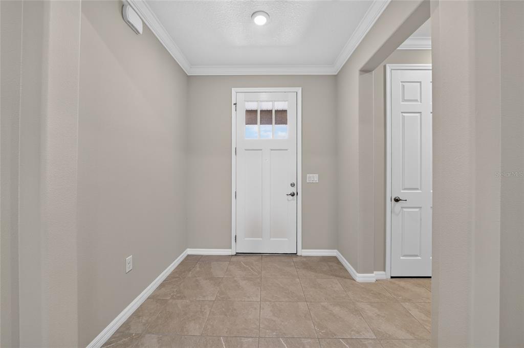 An entryway features beige walls, tiled flooring, a white front door, and a closet door — 9858 SW 90TH STREET, OCALA, FL