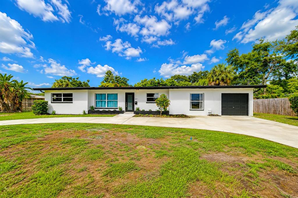 A single-story white house with a black trim, a garage, and a large concrete driveway — 6871 4TH STREET S, ST PETERSBURG, FL