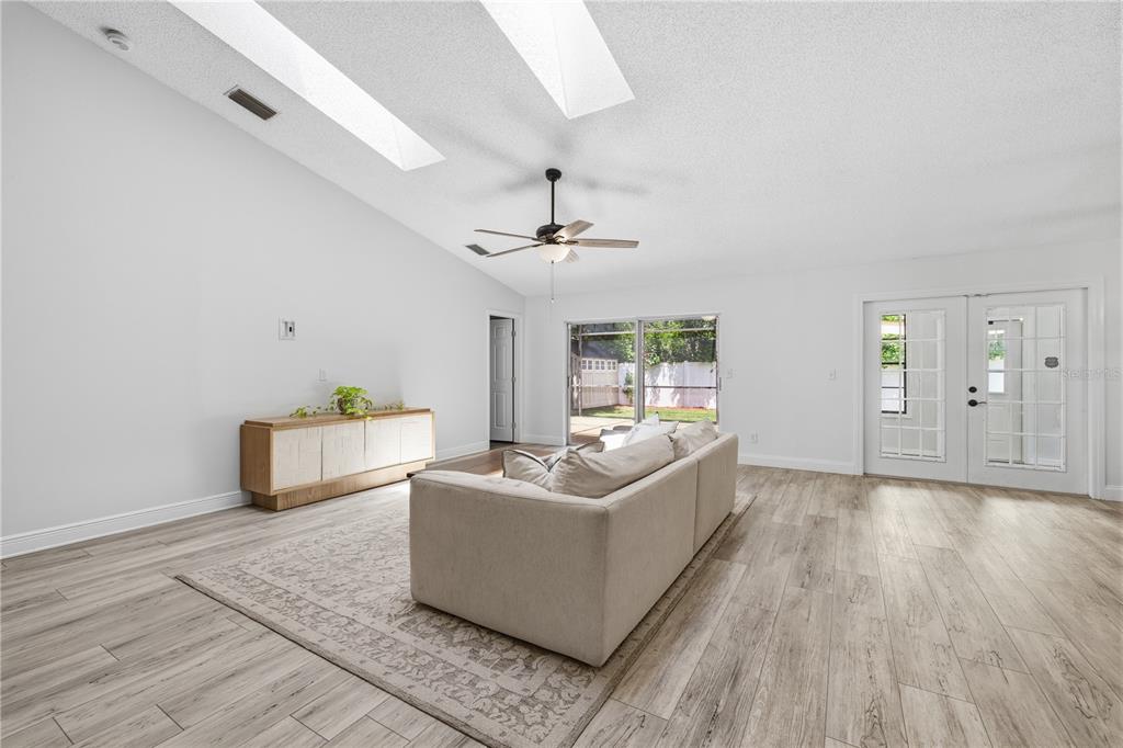 A living room features light wood-look flooring, a vaulted ceiling with skylights, and a sofa — 1570 CLUB DRIVE, TARPON SPRINGS, FL