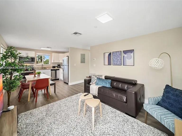 An open-concept living and dining area features a dark leather sofa and a wooden table — 2320 Garfield St, Hollywood FL 33020, HOLLYWOOD, FL