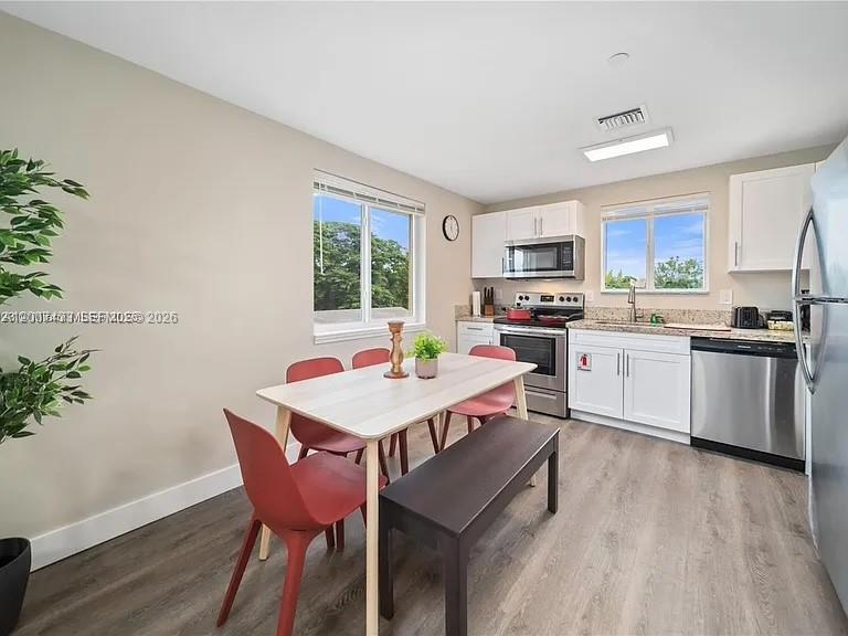 A dining area with a table and chairs sits adjacent to a modern kitchen — 2320 Garfield St, Hollywood FL 33020, HOLLYWOOD, FL