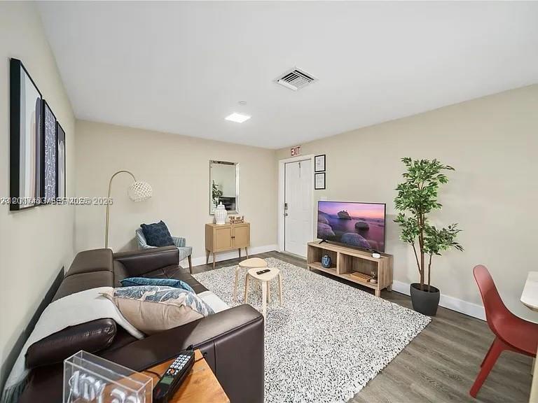 A living room features a dark leather sofa, a television on a stand, and a rug — 2320 Garfield St, Hollywood FL 33020, HOLLYWOOD, FL