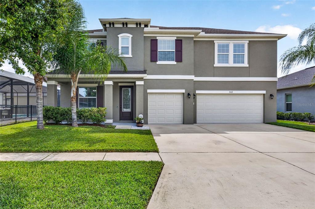 A two-story house with a gray stucco exterior, a two-car garage, and a front porch — 7109 BAY LAUREL COURT, WESLEY CHAPEL, FL
