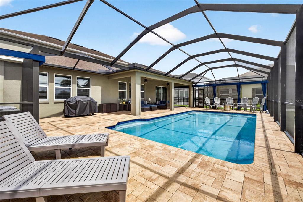 A screened-in patio features a rectangular swimming pool, lounge chairs, and a covered seating area — 7109 BAY LAUREL COURT, WESLEY CHAPEL, FL