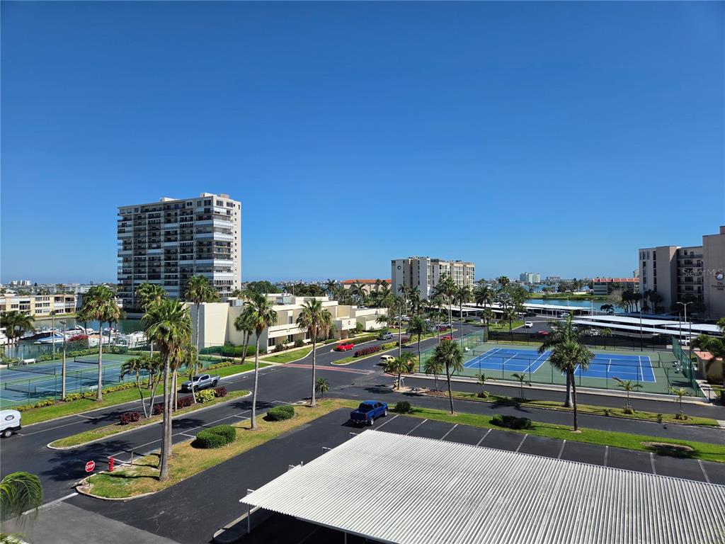An elevated view of a residential complex featuring tennis courts, parking, and palm trees — 7700 SUN ISLAND DRIVE S UNIT 503, SOUTH PASADENA, FL
