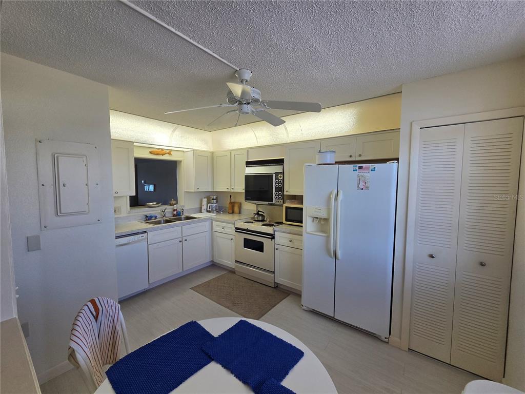 A kitchen features white cabinets, white appliances, a ceiling fan, and a small dining table — 7700 SUN ISLAND DRIVE S UNIT 503, SOUTH PASADENA, FL
