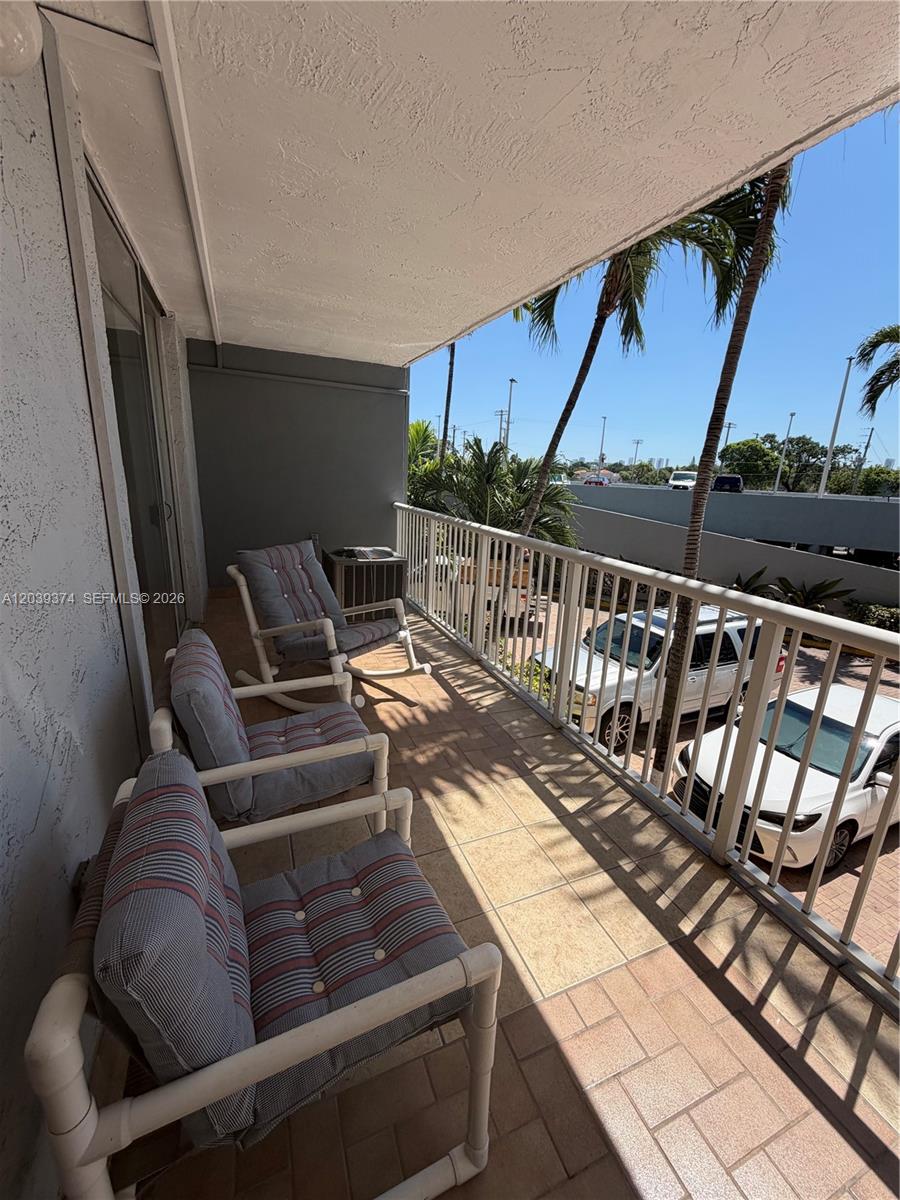 A balcony features three rocking chairs with striped cushions and a view of parked cars — 1800 NW 24th Ave # 220, Miami FL 33125, MIAMI, FL