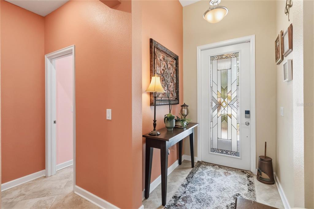 An entryway features a glass-paneled front door, a console table, and peach-colored walls — 1361 OLYMPIC CLUB BOULEVARD, CHAMPIONS GATE, FL