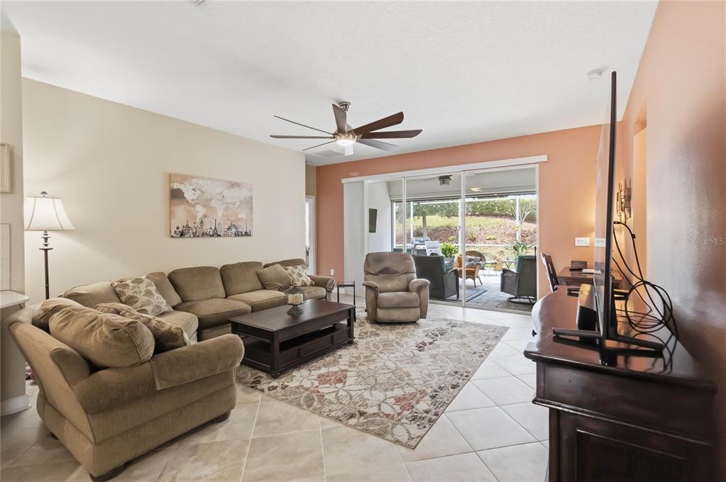 A living room features a sectional sofa, a recliner, a coffee table, and sliding glass doors — 1361 OLYMPIC CLUB BOULEVARD, CHAMPIONS GATE, FL