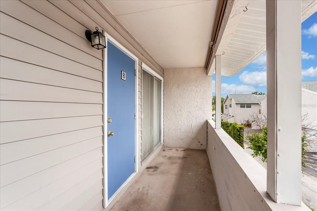 A blue door labeled B opens onto a covered outdoor balcony with light-colored siding — 2786 CURRY FORD ROAD UNIT 6B, ORLANDO, FL