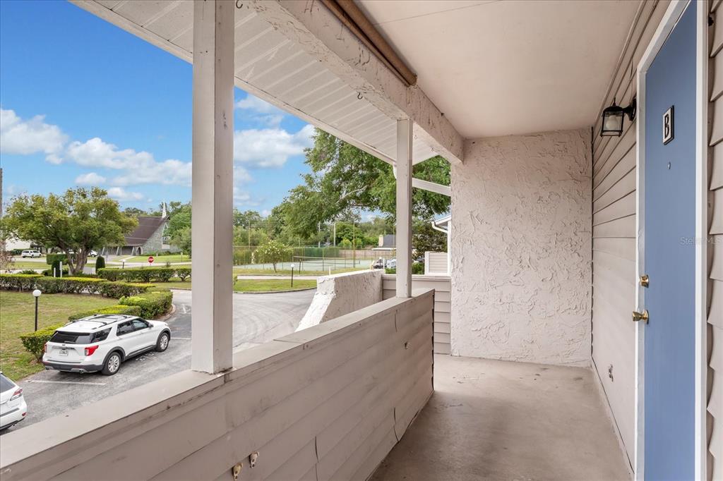 An outdoor balcony features a blue door, white siding, and a view of a parking lot — 2786 CURRY FORD ROAD UNIT 6B, ORLANDO, FL
