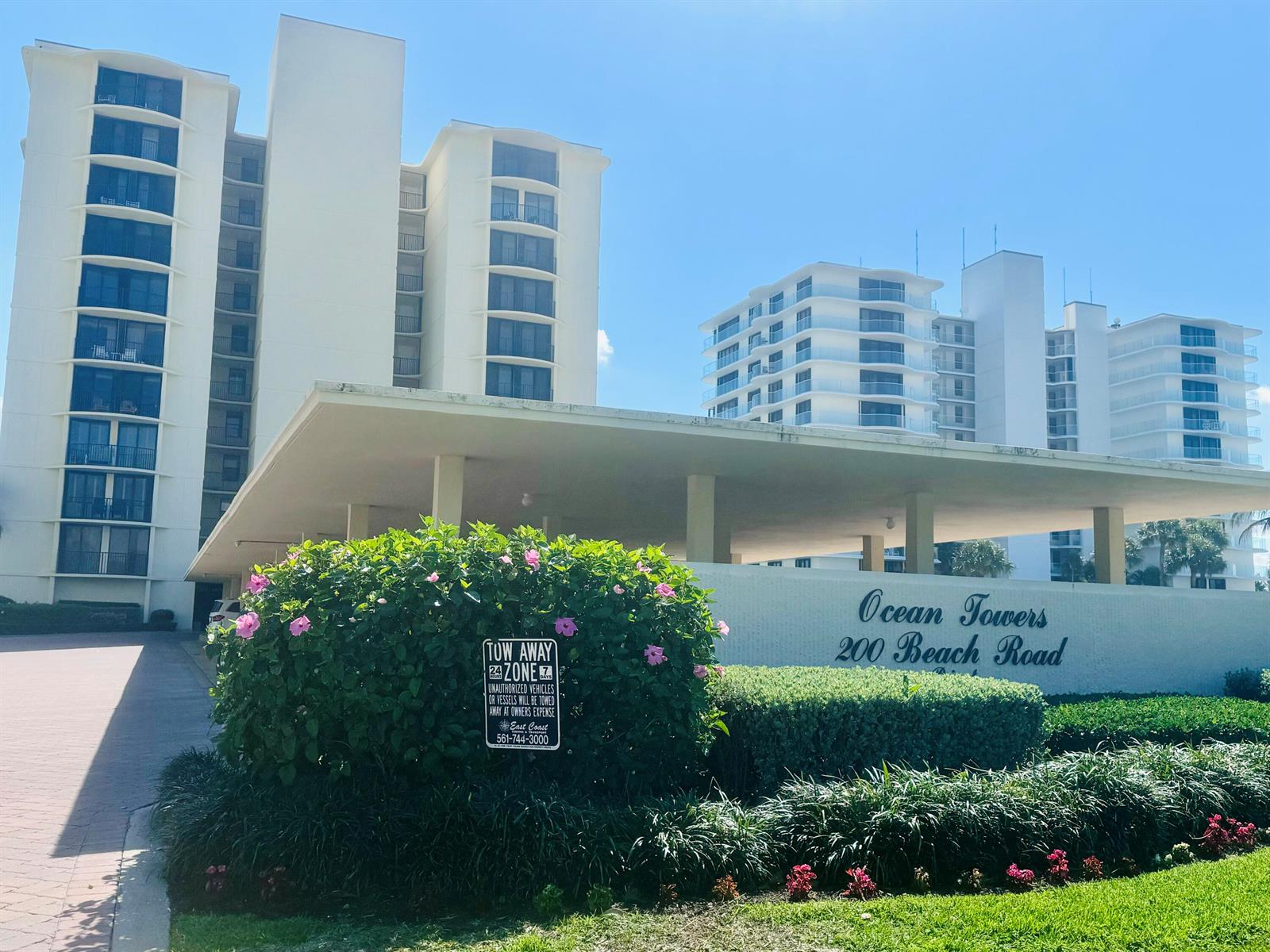 The exterior of a multi-story white apartment building with a covered entrance and landscaping — 200 S Beach Road # 403, Tequesta FL 33469, TEQUESTA, FL
