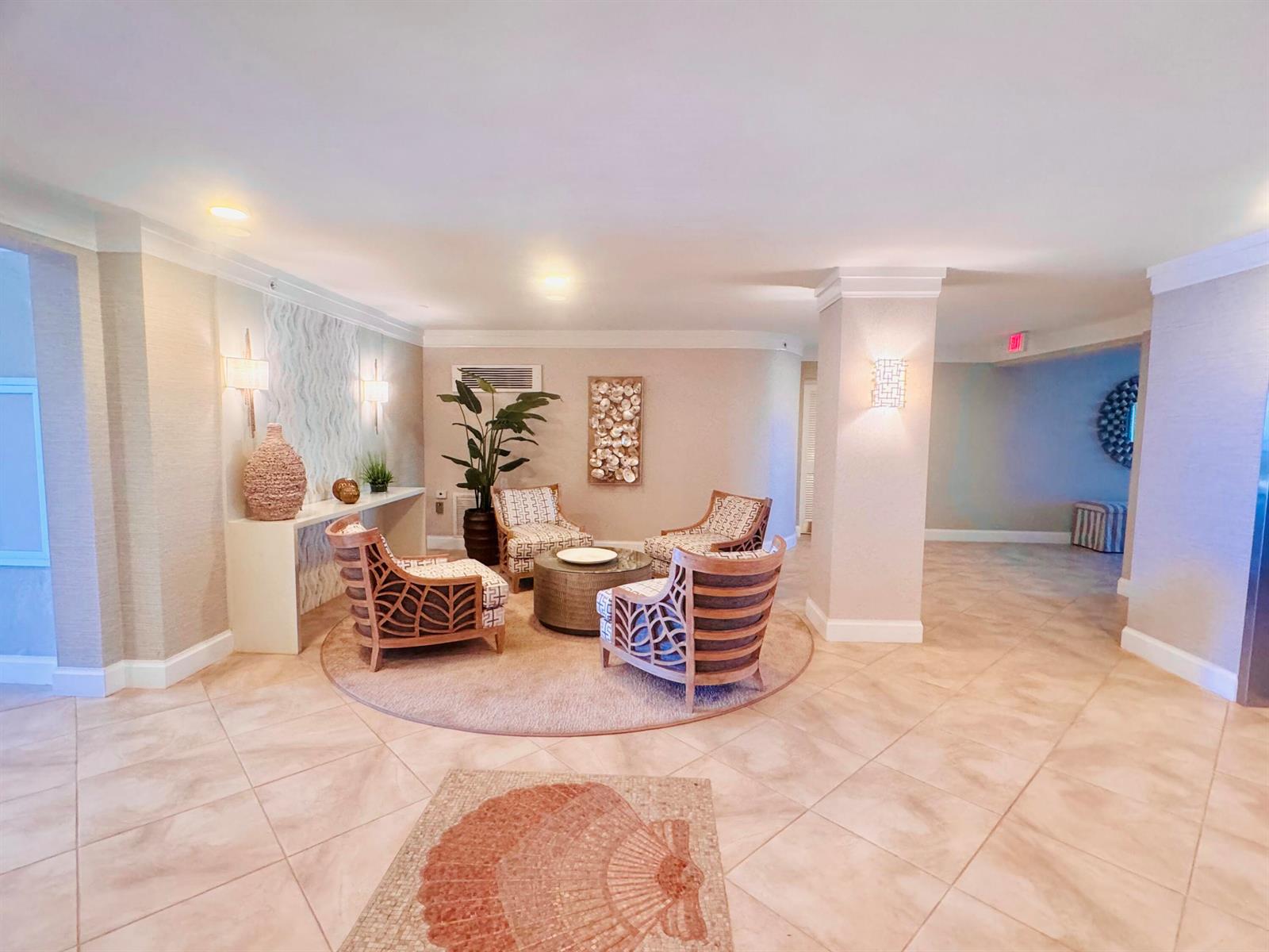 A lobby seating area features four patterned armchairs, a circular coffee table, and tile flooring — 200 S Beach Road # 403, Tequesta FL 33469, TEQUESTA, FL