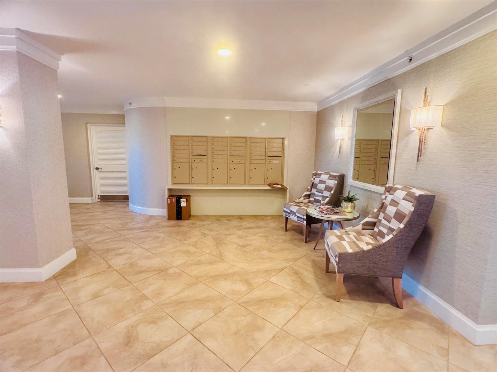 A lobby area features tiled floors, a wall of mailboxes, two patterned chairs, and sconce lighting — 200 S Beach Road # 403, Tequesta FL 33469, TEQUESTA, FL