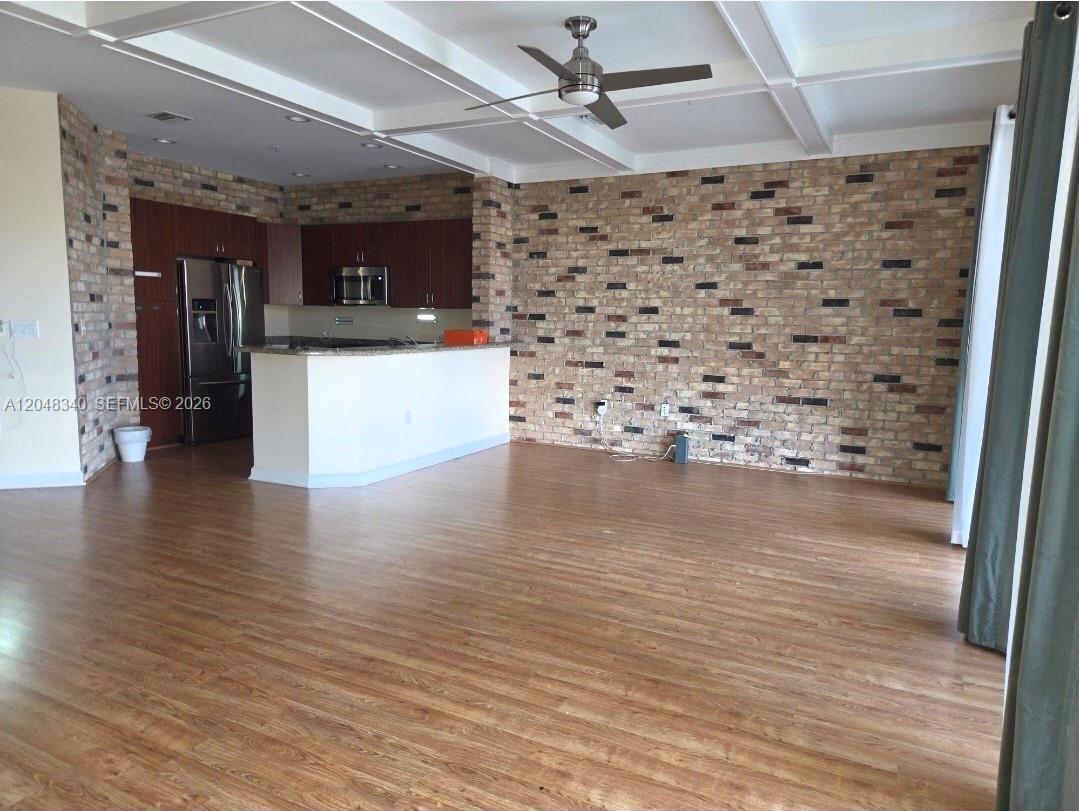 An open-concept living area features a kitchen with dark cabinets and a brick accent wall — 2900 NW 125th Ave # 319, Sunrise FL 33323, SUNRISE, FL