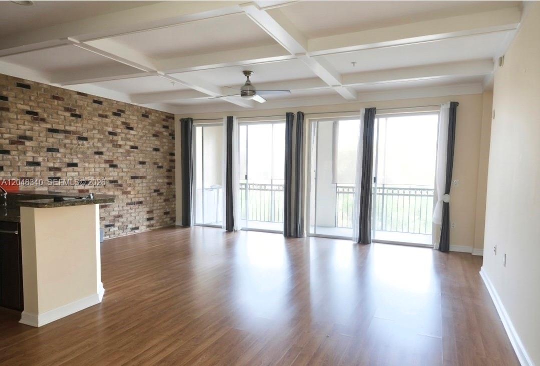 A living room features wood flooring, a brick accent wall, and a coffered ceiling — 2900 NW 125th Ave # 319, Sunrise FL 33323, SUNRISE, FL