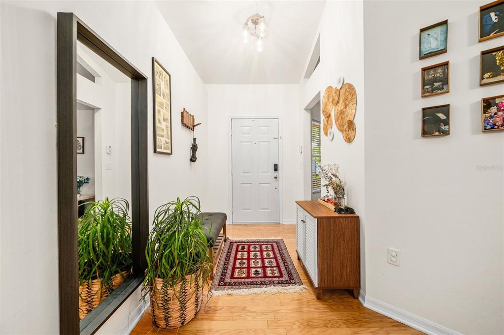An entryway features hardwood floors, a large wall mirror, a patterned rug, and a console table — 8725 NW 9TH PLACE, GAINESVILLE, FL