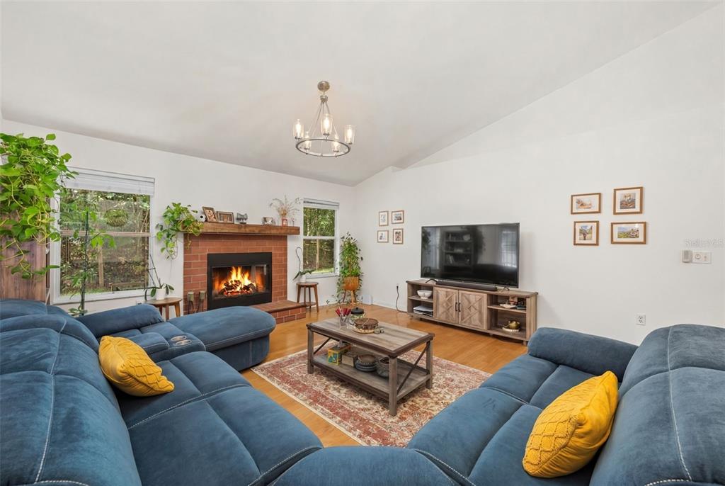 A living room features a brick fireplace, a blue sectional sofa, and a television console — 8725 NW 9TH PLACE, GAINESVILLE, FL