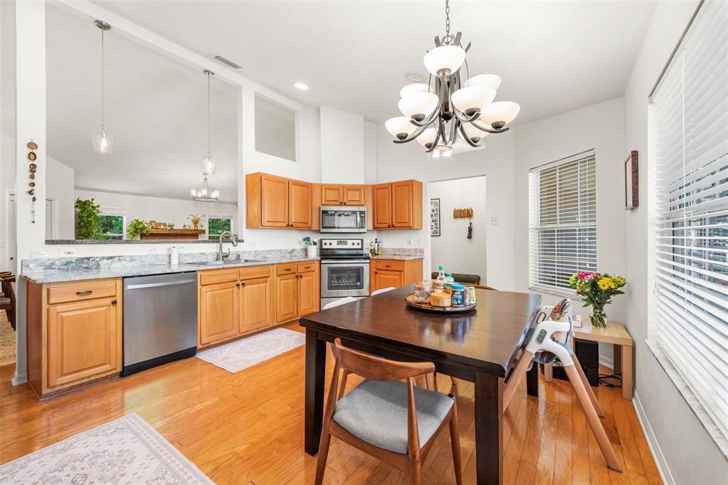 A kitchen features light wood cabinets, granite countertops, stainless steel appliances, and a dining table — 8725 NW 9TH PLACE, GAINESVILLE, FL