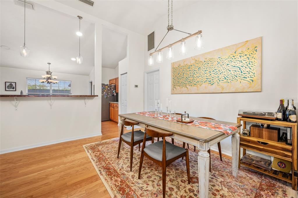 A dining room with a wooden table, patterned rug, and a large piece of wall art — 8725 NW 9TH PLACE, GAINESVILLE, FL