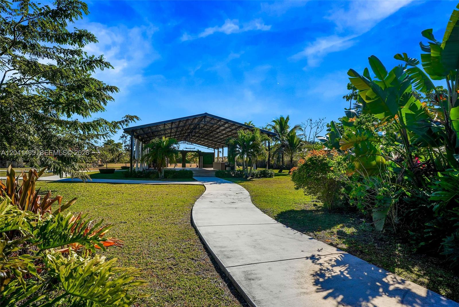A concrete path leads through a grassy yard toward an open-air pavilion with metal roofing — 13201 SW 197th Ave, Miami FL 33196, MIAMI, FL