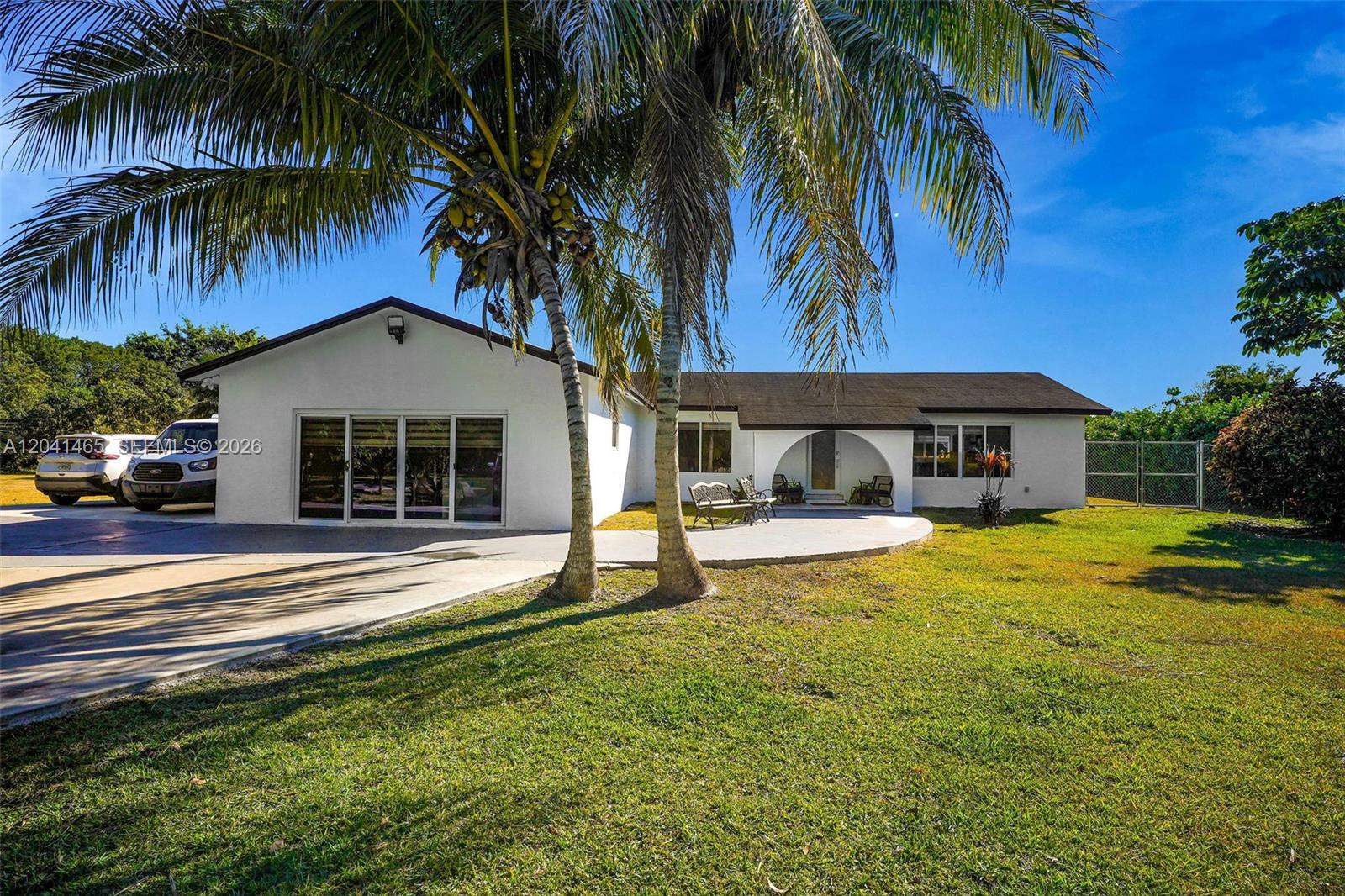 A single-story white house with a palm tree, concrete driveway, and arched entryway — 13201 SW 197th Ave, Miami FL 33196, MIAMI, FL