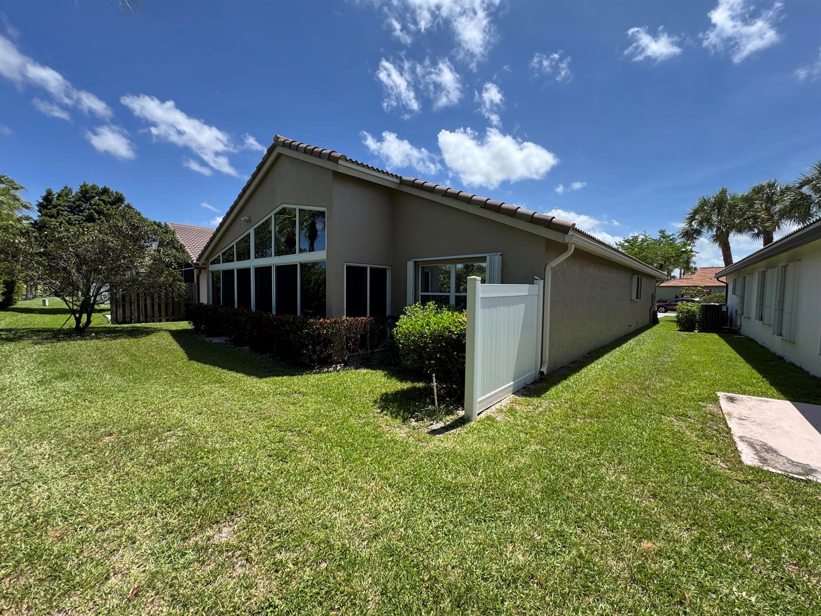 A tan house with a screened-in patio and a white privacy fence on a lawn — 6693 Sun River Road, Boynton Beach FL 33437, BOYNTON BEACH, FL