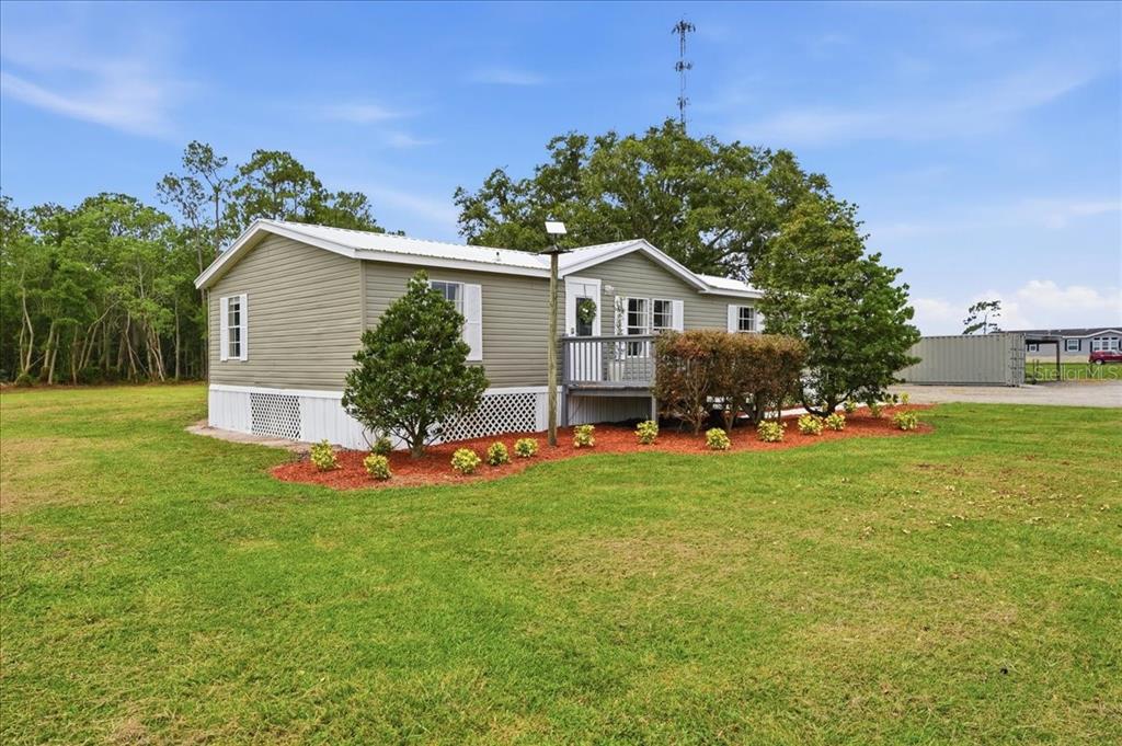 A single-story manufactured home with light green siding sits on a grassy lot — 4450 QUAIL ROOST RD, ST CLOUD, FL