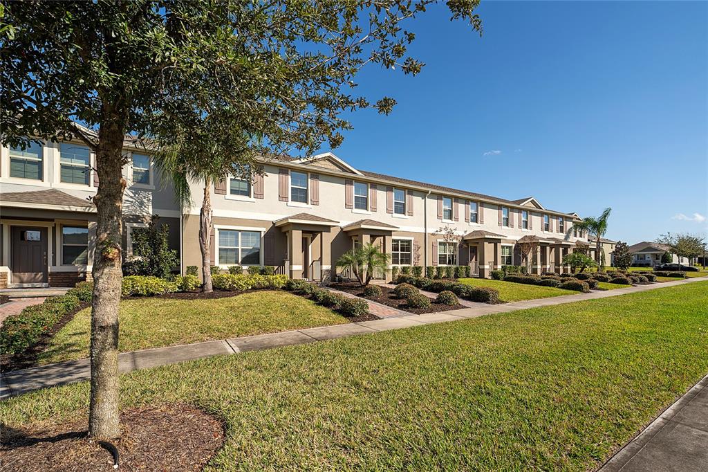A row of two-story townhomes with beige siding, shingled roofs, and manicured front lawns — 16931 RESEDA ALLEY, WINTER GARDEN, FL