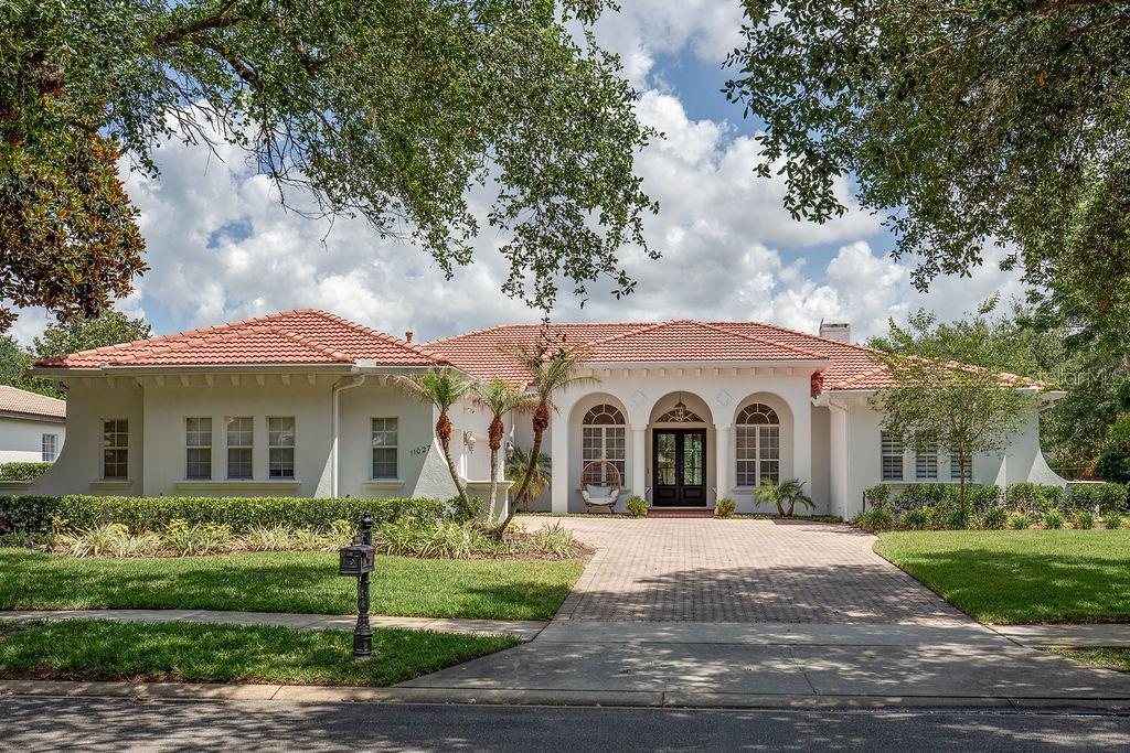 A single-story Mediterranean-style house with a red tile roof and a paved driveway — 11027 HAWKSHEAD COURT, WINDERMERE, FL