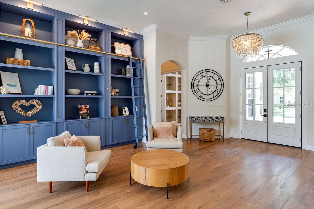 A living room features blue built-in bookshelves with a rolling ladder, two armchairs, and wood flooring — 11027 HAWKSHEAD COURT, WINDERMERE, FL