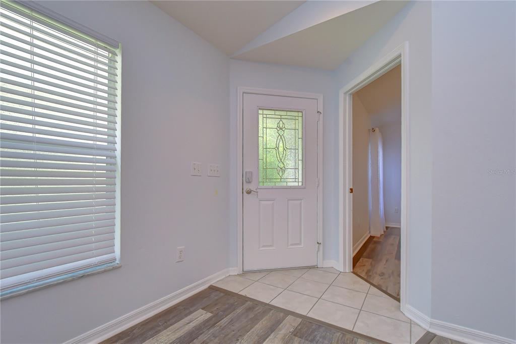 An entryway features a white front door with a decorative glass insert and tiled flooring — 6010 SKYLARKCREST DRIVE, LITHIA, FL