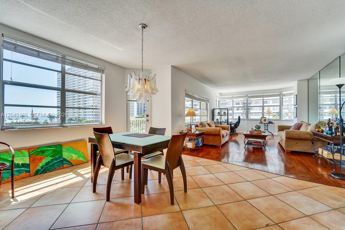 An open-concept dining and living area features tile and wood flooring with large windows — 1965 S Ocean Dr # 4G, Hallandale Beach FL 33009, HALLANDALE BEACH, FL