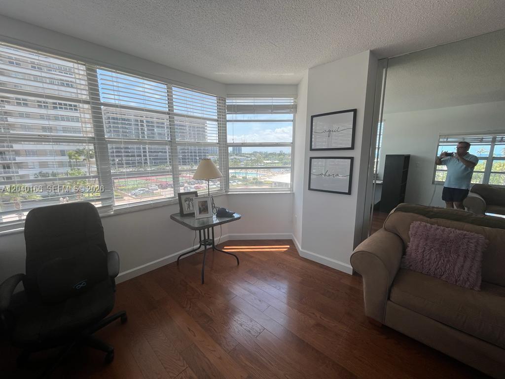 A living room with wood floors, large windows, a sofa, and a desk chair — 1965 S Ocean Dr # 4G, Hallandale Beach FL 33009, HALLANDALE BEACH, FL