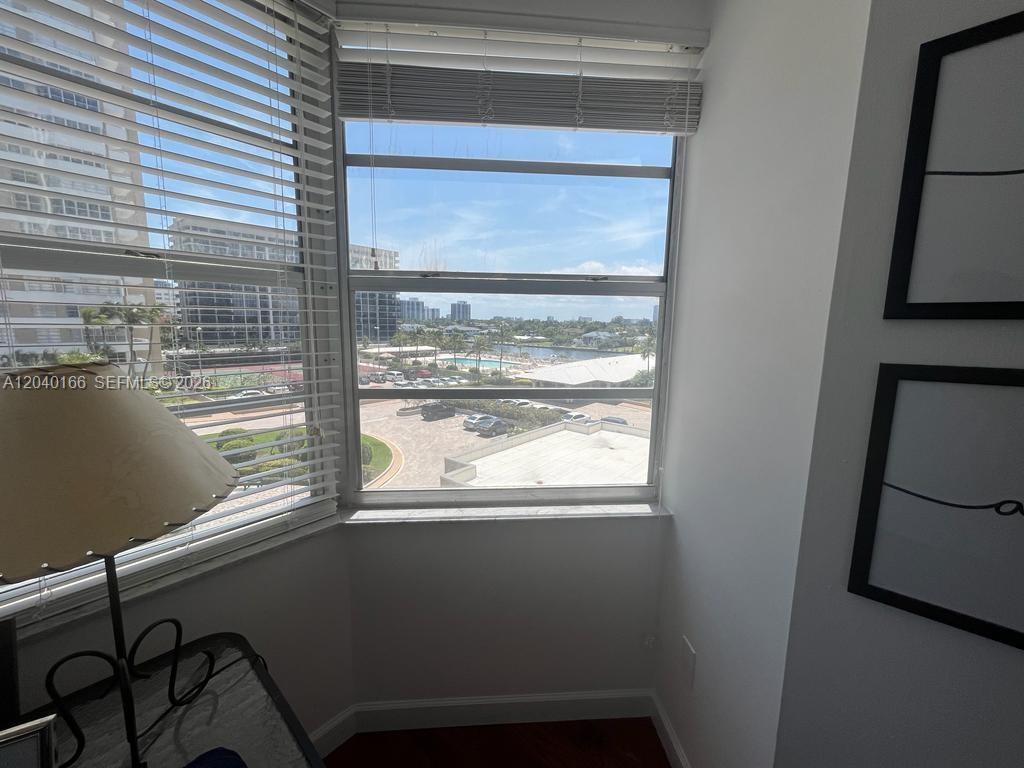 A corner window with white blinds overlooks a parking lot and a distant waterfront area — 1965 S Ocean Dr # 4G, Hallandale Beach FL 33009, HALLANDALE BEACH, FL