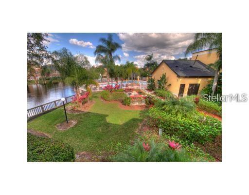 An outdoor view of a community pool, a small building, and a lake with landscaping — 5713 GATLIN AVENUE UNIT 211, ORLANDO, FL