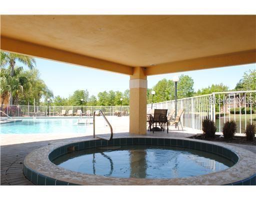 A circular hot tub sits on a paved patio beneath a covered pool deck area — 5713 GATLIN AVENUE UNIT 211, ORLANDO, FL