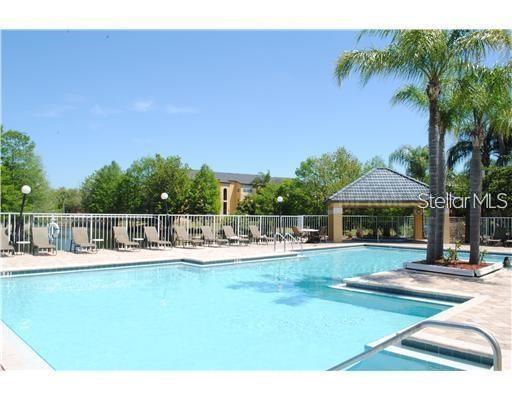 A swimming pool with lounge chairs and a covered pavilion under a clear blue sky — 5713 GATLIN AVENUE UNIT 211, ORLANDO, FL