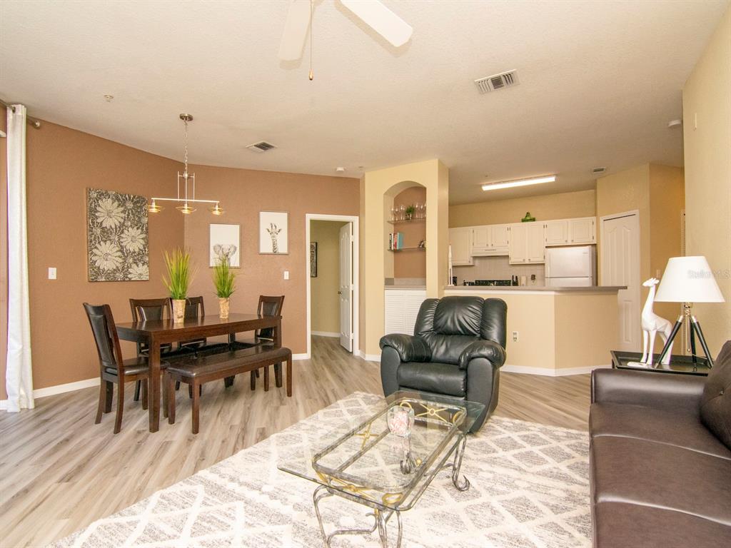An open-concept living and dining area features light wood-look flooring and a neutral color palette — 5815 LEGACY CRESCENT PLACE UNIT 202, RIVERVIEW, FL