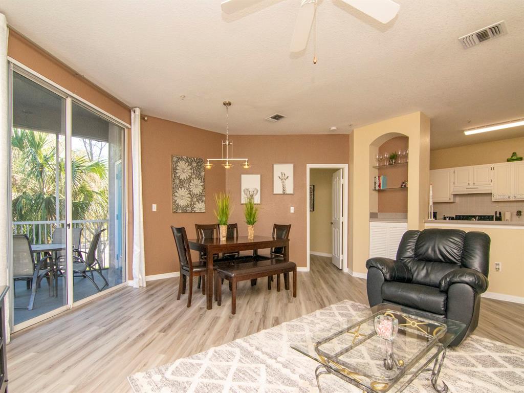 A dining area with a table and chairs sits next to a living room space — 5815 LEGACY CRESCENT PLACE UNIT 202, RIVERVIEW, FL