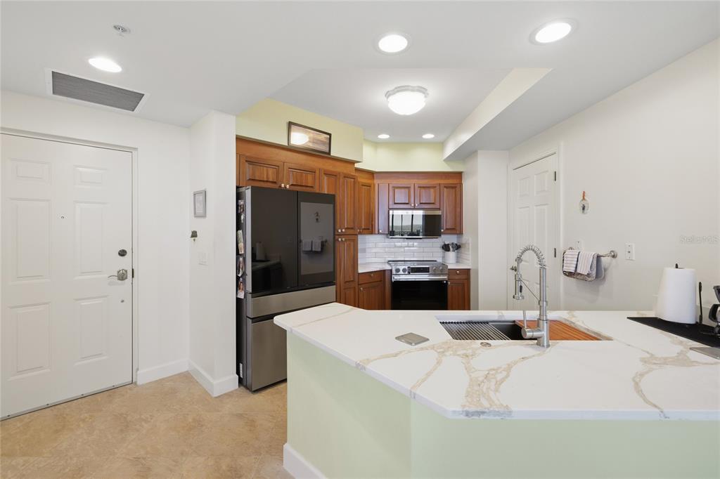 A kitchen features wood cabinets, stainless steel appliances, and a white quartz-topped peninsula island — 3191 MATECUMBE KEY ROAD UNIT 701, PUNTA GORDA, FL