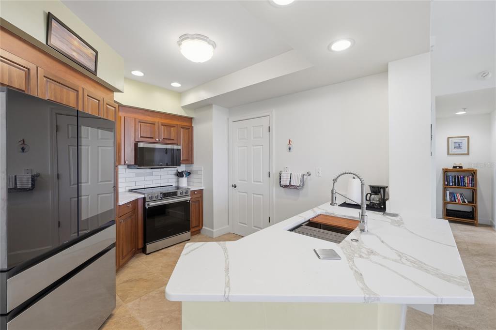 A kitchen features wood cabinets, stainless steel appliances, a white island, and tile flooring — 3191 MATECUMBE KEY ROAD UNIT 701, PUNTA GORDA, FL