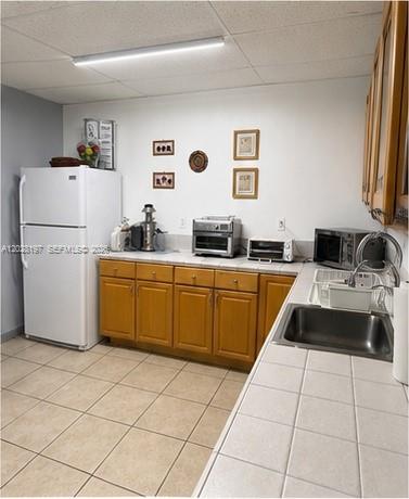 A kitchen features white appliances, wooden cabinets, tiled countertops, and a stainless steel sink — 5555 NW 74th Ave # 5555, Miami FL 33166, MIAMI, FL